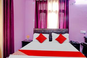 um quarto com uma cama vermelha e branca com almofadas vermelhas em Flagship Hotel The Pinkcity em Patna