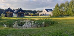 a house with a pond in the middle of a field at Domki Gorczyca in Płaska