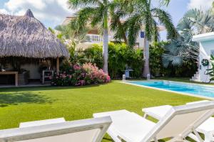 un patio del complejo con piscina y palmeras en Stylish 4 Bedroom Modern Villa Design, Walking Distance From The Beach en Jan Thiel