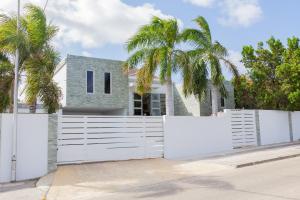 einen weißen Zaun vor einem Haus mit Palmen in der Unterkunft Stylish 4 Bedroom Modern Villa Design, Walking Distance From The Beach in Jan Thiel
