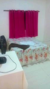 POUSADA CASA AMARELA في شابادا دوس غيماريش: غرفة مع سرير ونافذة وردية