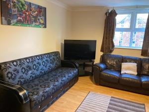 sala de estar con 2 sofás de cuero y TV de pantalla plana en Cosy Apartment, en Mánchester