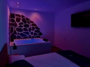 Habitación púrpura con bañera y pared de roca en Jacuzzi en Benaocaz by CadizTime Apartments en Benaocaz