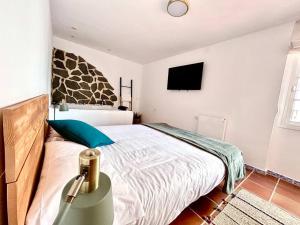 a bedroom with a bed and a tv on the wall at Jacuzzi en Benaocaz by CadizTime Apartments in Benaocaz