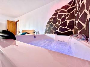 y baño con bañera y pared de piedra. en Jacuzzi en Benaocaz by CadizTime Apartments en Benaocaz