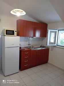 een keuken met een witte koelkast en houten kasten bij Apartments Panorama in Korčula