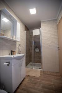 een badkamer met een witte wastafel en een douche bij Apartmani Lara Modruš-Kuća za odmor in Modruš