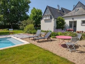 a patio with a table and chairs next to a pool at Le Chêne Olivet in Olivet