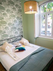 ein Bett mit zwei Kissen darauf in einem Zimmer mit Fenster in der Unterkunft Setubal History - By Y Concept in Setúbal