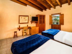 a bedroom with two beds and a desk with a television at Posada Real del Valle in Valle de Bravo