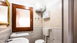 bagno con servizi igienici, lavandino e specchio di Casa Vacanze Mulvoni Aiosardegna a Pula