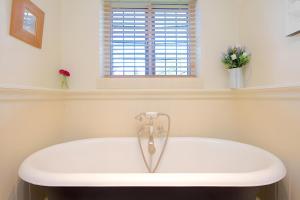 a bath tub in a bathroom with a window at The Thatch in Chipping Campden