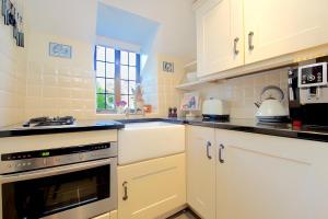 a kitchen with white cabinets and a stove top oven at The Thatch in Chipping Campden