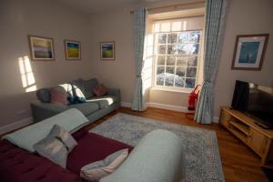uma sala de estar com dois sofás e uma televisão em The Bothy at Bowhill em Selkirk