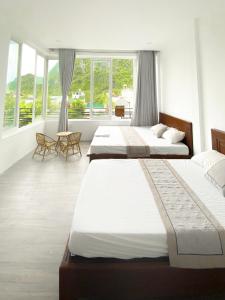 two beds in a bedroom with windows and a room at Hideaway Homestay in Phong Nha