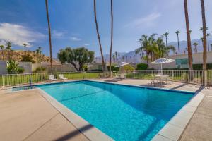 uma piscina com cadeiras e guarda-sóis em Sunny Palm Springs Townhome with Pool Access! em Palm Springs