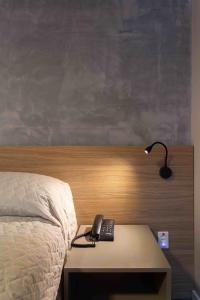 a bed with a desk with a lamp and a phone on it at Hotel Dom Rafael Executivo in Santa Maria