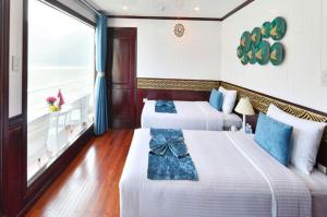 Halong Sapphire Cruises في ها لونغ: سريرين في غرفة الفندق مع شرفة