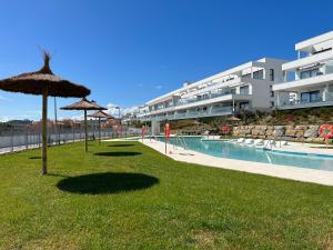 a lawn with umbrellas and a swimming pool at Via Celere 2329 Luxury apartment with Sea View in Casares