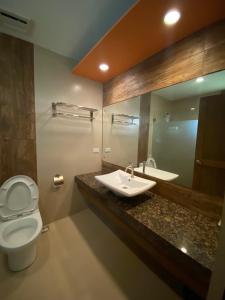 un bagno con lavandino, WC e specchio di El Puerto Marina Beach Resort & Vacation Club a Lingayen