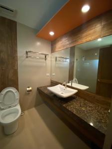 a bathroom with a sink and a toilet and a mirror at El Puerto Marina Beach Resort & Vacation Club in Lingayen