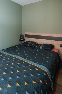 a bedroom with a bed with a blue and yellow comforter at Appartement 2 pièces L'industriel en centre-ville de Cambrai in Cambrai