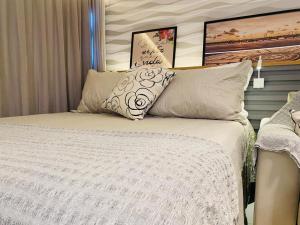 ein Schlafzimmer mit einem weißen Bett mit Kissen in der Unterkunft FLAT ILHA DO LEITE - DENTRO PÓLO MÉDICO in Recife