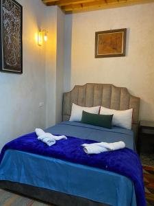 - une chambre avec un lit bleu et des serviettes dans l'établissement RIAD Tamazouzt, à Essaouira