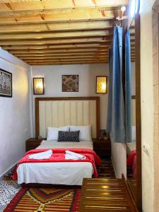 - une chambre avec un lit et une couverture rouge dans l'établissement RIAD Tamazouzt, à Essaouira