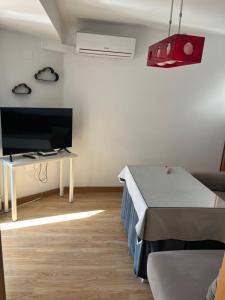 - un salon avec une télévision, un lit et une table dans l'établissement Bonito apartamento en Granada (zona palacio congresos y metro), à Grenade