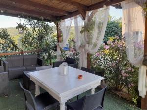 uma mesa branca e cadeiras sob uma pérgola em Madama Langa Country House con piscina nelle vigne em Montelupo Albese