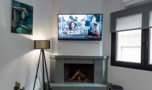 a living room with a tv above a fireplace at Frourio Lodge Α2 in Larisa
