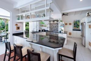 a kitchen with white cabinets and a counter with chairs at Hectors House Blue Sky Luxury in Christ Church
