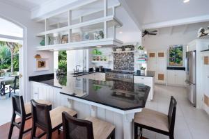 Una cocina con gabinetes blancos y un mostrador con sillas. en Hectors House Blue Sky Luxury, en Christ Church