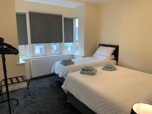 two beds in a room with two windows at Waterloo Sunset in Blackpool