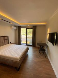 a bedroom with a bed and a table and a television at New apartment with pool near the sea in Akbük
