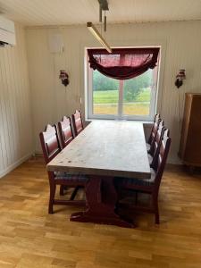 a dining room table with chairs and a large window at Fjellstad Gård - 2 minutes from E6 and 5 minutes drive from Steinkjer city in Steinkjer