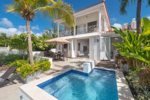 a villa with a swimming pool in front of a house at Exceptional Beachfront Living - Milord Sunsets home in Saint James