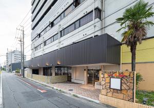 a building with a palm tree next to a street at Hotel Sun in Takasaki