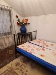 een bed in een kamer met een vaas met bloemen bij Apartment Kula in Gračanica