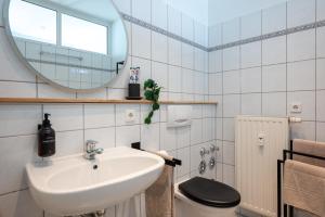 ein Badezimmer mit einem Waschbecken, einem WC und einem Spiegel in der Unterkunft LE Vacation 3-Room-Apartment 67qm, Küche, Netflix, Free-TV in Schkeuditz