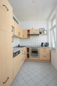 a kitchen with wooden cabinets and a white tile floor at LE Vacation 3-Room-Apartment 67qm, Küche, Netflix, Free-TV in Schkeuditz