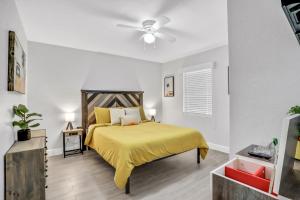 a bedroom with a yellow bed and a ceiling fan at Baycation on Arch in Tampa
