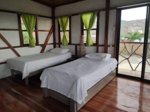 2 camas en una habitación con cortinas verdes en Cayo Ecovillage, en Puerto Cayo