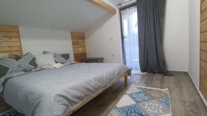 a bedroom with a large bed and a large window at Chalet Alina in Borşa