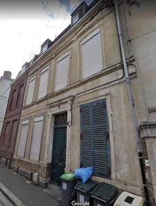 un antiguo edificio con una puerta verde y un cubo de basura en Appartement 2 pièces L'industriel en centre-ville de Cambrai, en Cambrai