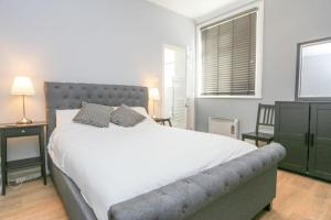 1 dormitorio con 1 cama grande y cabecero gris en Southsea Historic Gem - Elegant Apartments, en Portsmouth