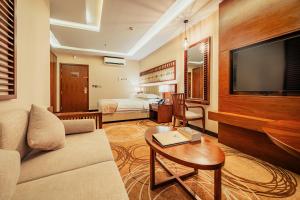 een woonkamer met een bank en een flatscreen-tv bij فندق إيفا إن in Abha