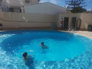 twee personen zwemmen in een groot blauw zwembad bij Beira Mar Apartment in Portimão