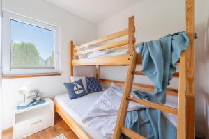 a bedroom with bunk beds and a ladder at Białe Żagle - domki nad morzem in Kopań